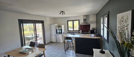 Eine moderne Küche mit Essbereich, großen Fenstern und Blick ins Freie.