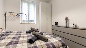 Un dormitorio con cama, cómoda, ventana y perchero.