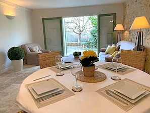 Un comedor con una mesa redonda para cuatro personas, una planta en maceta y vistas al exterior.