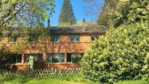 A two-story house with a brick exterior, a wooden fence, and a well-maintained garden.