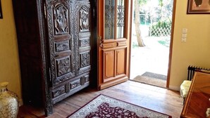 A wooden cabinet with intricate carvings, a wooden door with glass panels, and a patterned rug on a wooden floor.