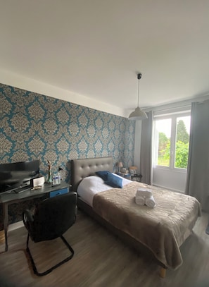 A bedroom with a bed, a desk, a chair, a TV, and a window with a view of greenery. - Serene bed & breakfast with WiFi in charming Barlest (Barlest)