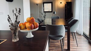 A modern dining area with a wooden table, grey chairs, and a white cake stand holding apples and dried flowers. - Idyllic mountain chalet "Platzl" in Vöran - your retreat in the Alps (Vöran)