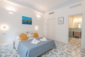 A hotel room with a bed, a nightstand, a bathroom with a mirror, and a door leading to another room. - Murice House - Amalfi (Amalfi)