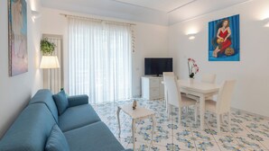 A modern living room with a blue sofa, a dining table with chairs, a TV, and a painting on the wall. - House Murice- Amalfi (Amalfi)