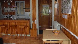 A wooden-paneled room with a kitchen area, a dining table with chairs, and a door leading to another room. - 10 minutes from GOURETTE and the Pyrenees National Park SUPERB APARTMENT (Eaux-Bonnes)