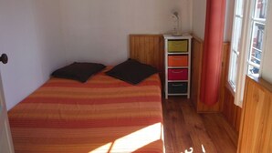 A small, single-bed room with a wooden floor, a bedside table with a lamp, and a window with curtains. - 10 minutes from GOURETTE and the Pyrenees National Park SUPERB APARTMENT (Eaux-Bonnes)