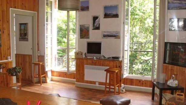 A cozy room with wooden walls, a large window with a view of greenery, a television, and a fireplace. - 10 minutes from GOURETTE and the Pyrenees National Park SUPERB APARTMENT (Eaux-Bonnes)