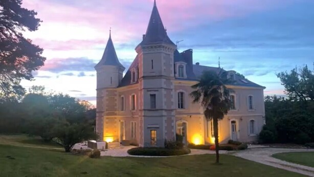Un grand bâtiment historique doté de nombreuses tours et d’une pelouse bien entretenue.