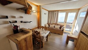 Ein gemütliches Blockhaus-Interieur mit einem Holzesstisch, Stühlen, einer Couch und einer kleinen Küchenzeile.