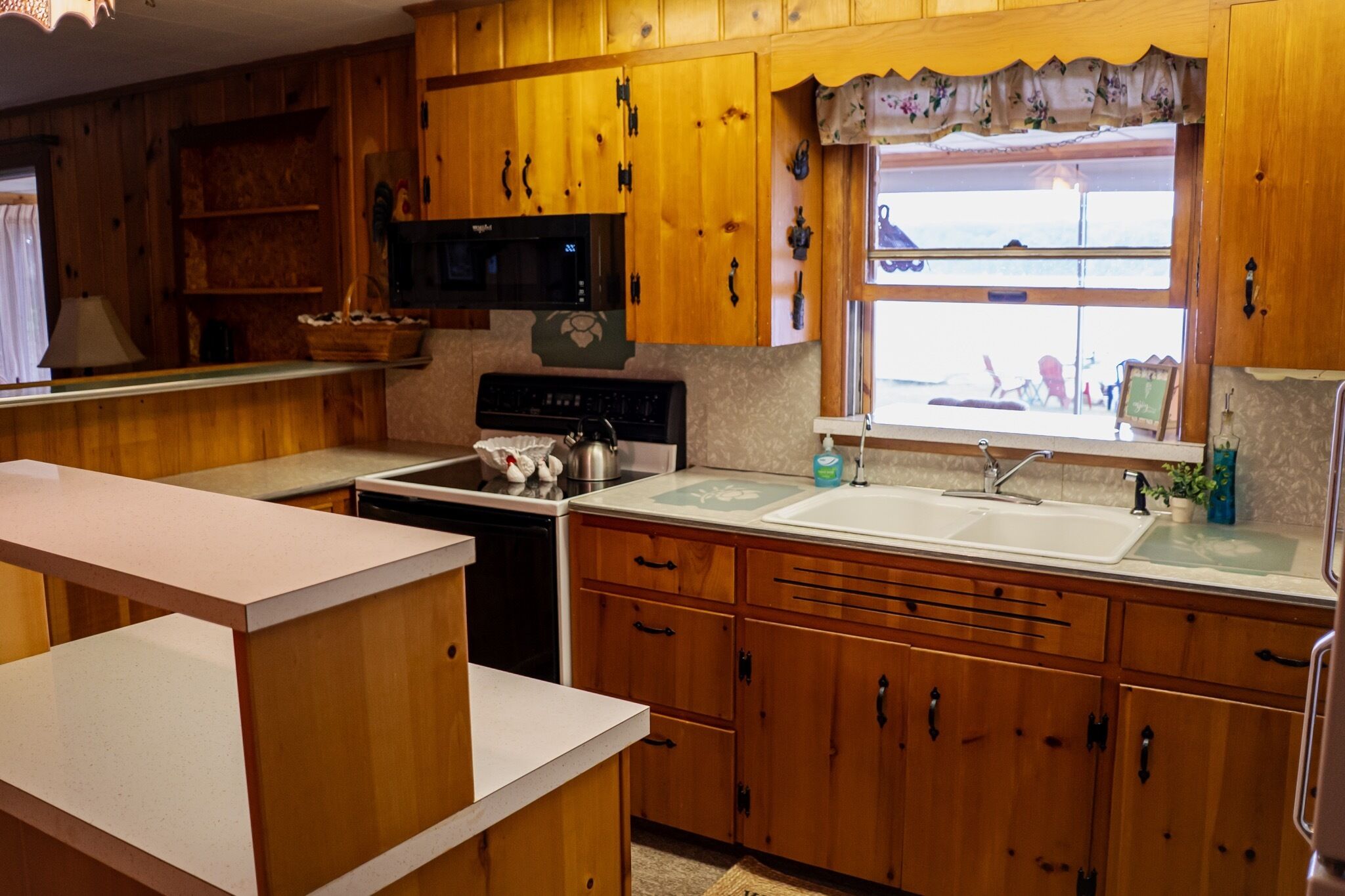 A kitchen with wooden cabinets, a microwave, a stove, and a sink.