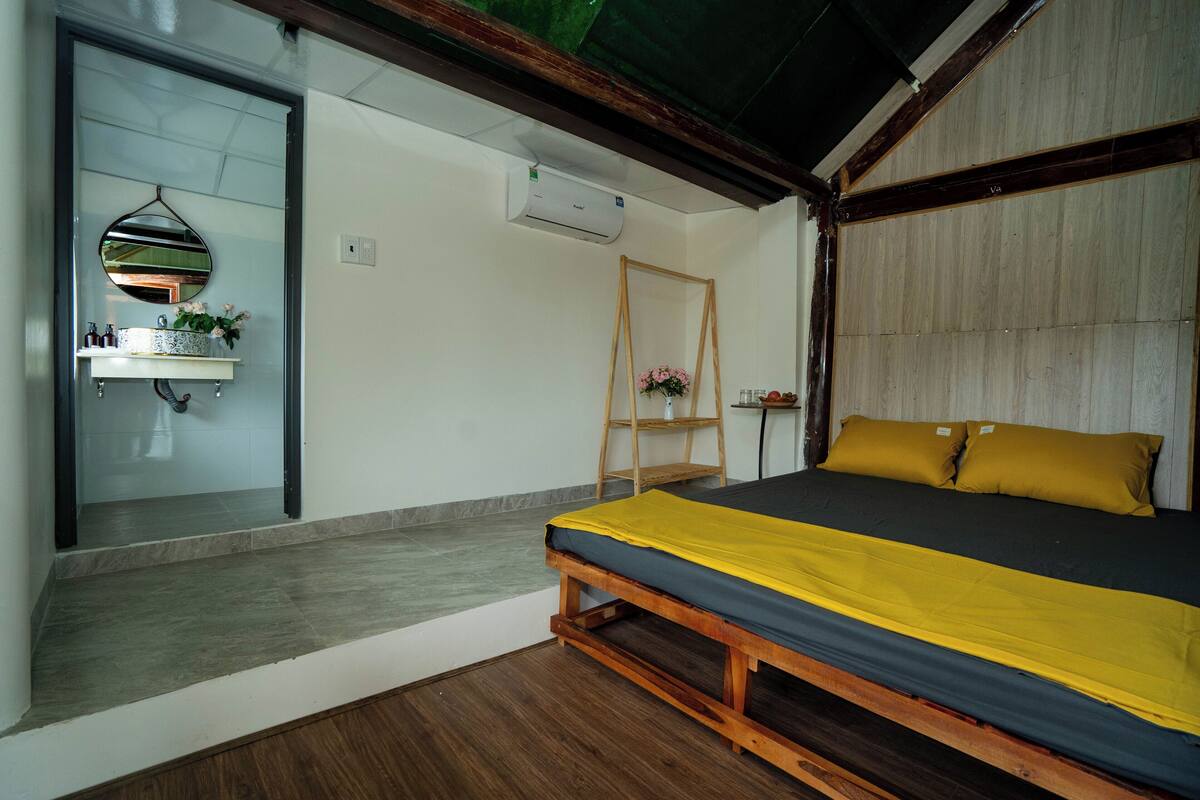 Une chambre à coucher avec un lit, une tête de lit en bois, un miroir, une étagère avec des articles de toilette et une petite échelle en bois.