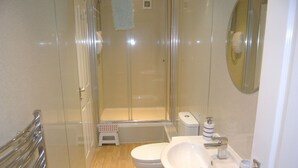 Un baño moderno con cabina de ducha de vidrio, inodoro blanco y lavabo con espejo.
