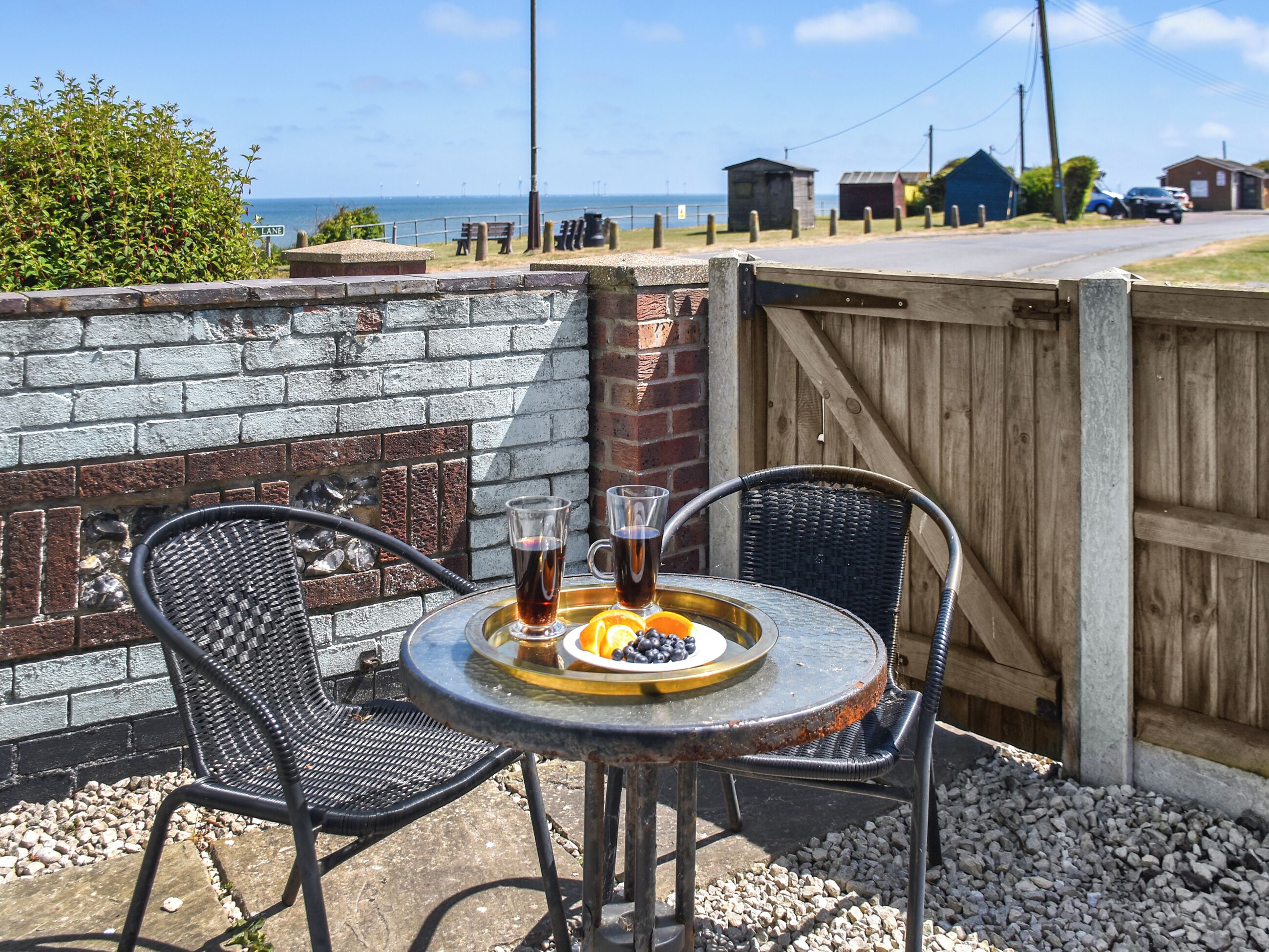 An outdoor seating area with a table, two chairs, and a tray with drinks and fruit.