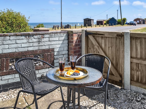 An outdoor seating area with a table, two chairs, and a tray with drinks and fruit.