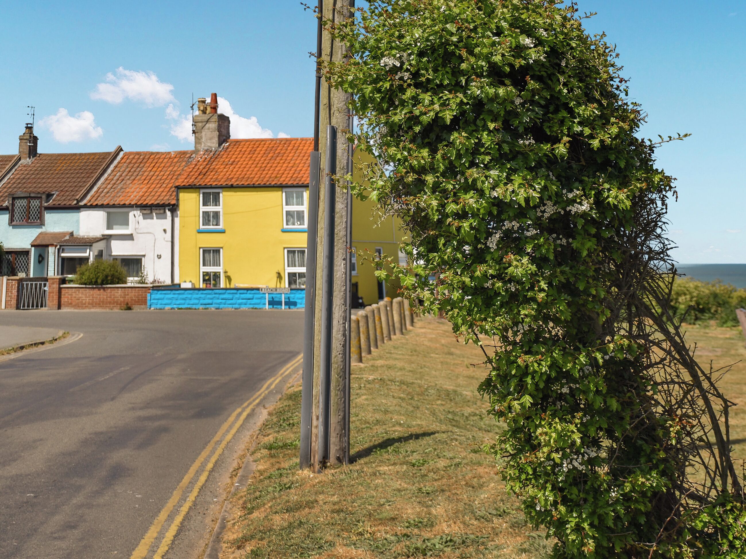 Une rue résidentielle bordée de maisons, avec un ciel dégagé et une zone herbeuse.