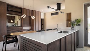 A modern kitchen with a central island, pendant lighting, and a large mirror. - Villa Portokalea, 200m From The Beach, Heated Pool (CHANIA)