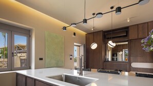 A modern kitchen with a large island, stainless steel sink, and pendant lighting. - Villa Portokalea, 200m From The Beach, Heated Pool (CHANIA)
