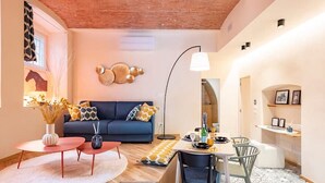Een moderne woonkamer met een blauwe bank, een eettafel met stoelen, een salontafel en een vloerlamp.