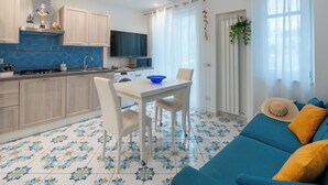 Una cocina moderna con comedor, televisor y sofá con cojines.