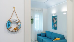 Una habitación con un sofá azul, un cartel de bienvenida en la pared y una pintura.