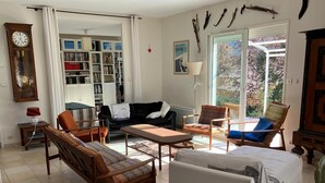 Un salon spacieux comprenant un canapé, des fauteuils, une table basse et une bibliothèque remplie de livres.
