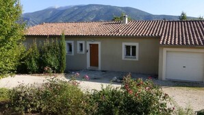 Une maison de plain-pied avec un toit recouvert de tuiles, une porte d’entrée et une porte de garage.