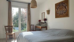 Une chambre à coucher comprenant un lit, un bureau, une chaise, une lampe suspendue et un élément décoratif mural.