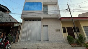 A multi-story building with a garage door, a balcony, and a visible power line. - YURIMAGUAS APARTMENTS (Yurimaguas)