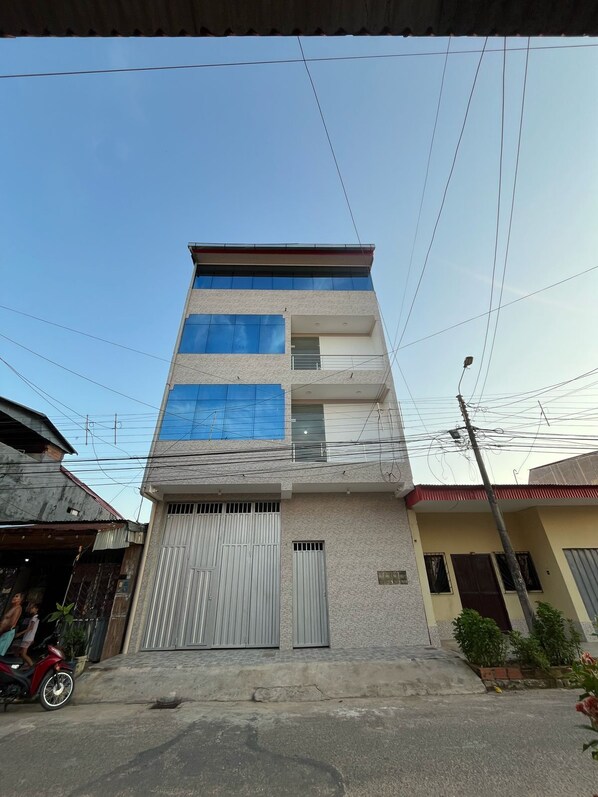 Un edificio de varios pisos con una puerta de garaje, un balcón y una línea de electricidad visible.