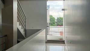 A modern interior with a staircase, a large glass door leading outside, and a ceiling light. - YURIMAGUAS APARTMENTS (Yurimaguas)