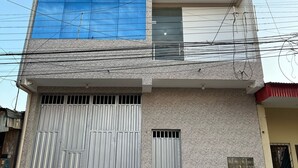 A multi-story building with a garage door, large windows, and a balcony. - YURIMAGUAS APARTMENTS (Yurimaguas)