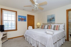 Ein Schlafzimmer mit einem Bett, Deckenventilator, einer Tür, einem Fenster und einem Bild an der Wand.