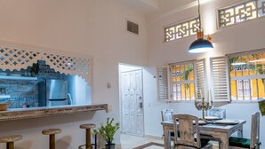 A dining area with a wooden table and chairs, a hanging light fixture, and a decorative plant. - Ayos - 1BDR Apto céntrico Edificio Ayos (Cartagena)