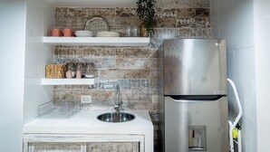A kitchen with a stainless steel refrigerator, white countertops, and a rustic backsplash. - Ayos - 1BDR Apto céntrico Edificio Ayos (Cartagena)