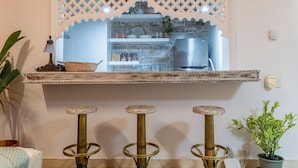 A kitchen with a wooden shelf above a bar area, a refrigerator, and a potted plant. - Ayos - 1BDR Apto céntrico Edificio Ayos (Cartagena)