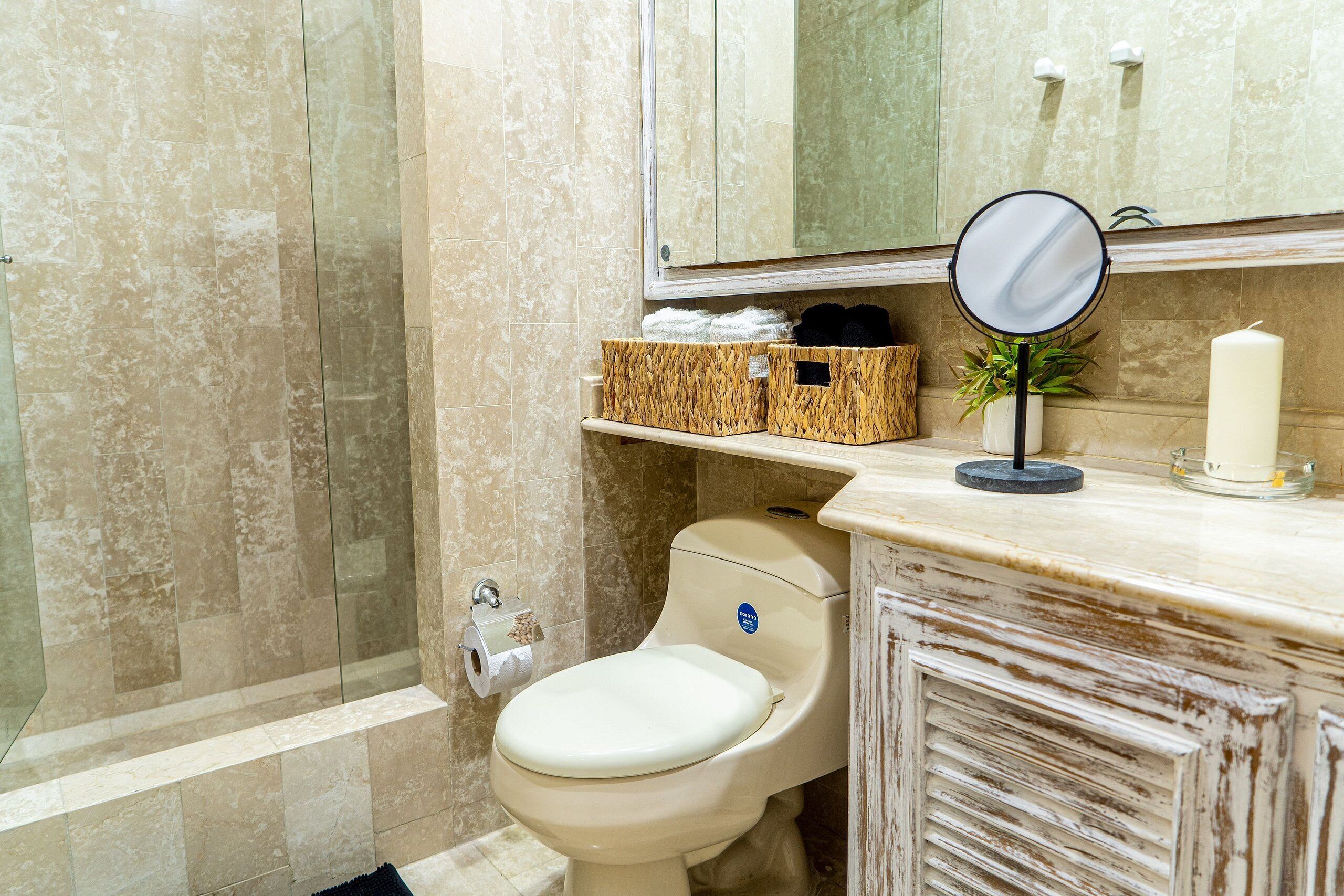 Une salle de bain comprenant des toilettes, un miroir, un lavabo et un espace douche.