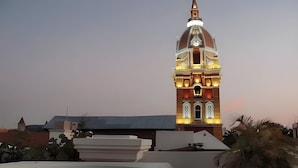 A building with a prominent dome and a clock tower, surrounded by potted plants and a pool. - Ayos - 1BDR Apto céntrico Edificio Ayos (Cartagena)