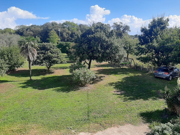 A grassy area with trees and a parked car. - Bedroom Apartment • Large Garden • 350m from Beach • A/C (Santa-Maria-Poggio)