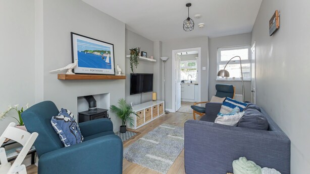 A modern living room with a TV, sofa, and a framed picture of a harbor. - Charming 2-Bedroom House in Portaferry – Perfect for a Cosy Getaway (Portaferry)