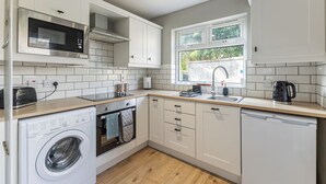 A compact kitchen with a washing machine, microwave, and dishwasher. - Charming 2-Bedroom House in Portaferry – Perfect for a Cosy Getaway (Portaferry)