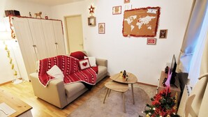 A cozy living room with a sofa, a small round table, and a Christmas tree. - Au Kugelhopf Doré - Historical Center (Colmar)