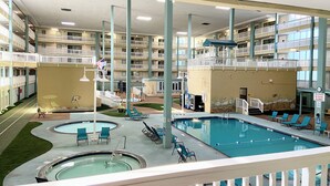 Ein Poolbereich im Innenbereich mit mehreren Balkonebenen, Liegestühlen und einem Pool mit Sprungbrett.