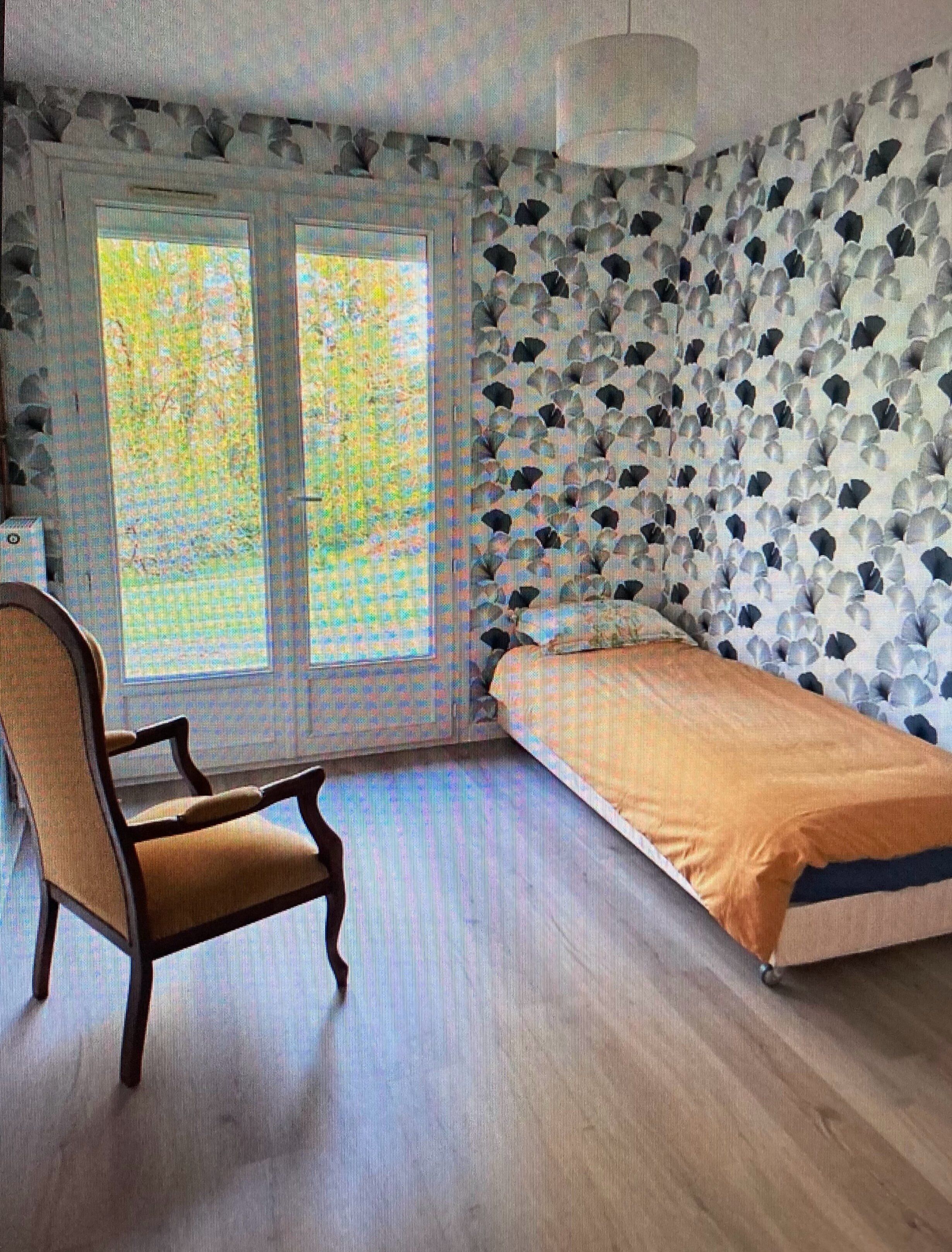 A bedroom with a bed, a chair, and a window.