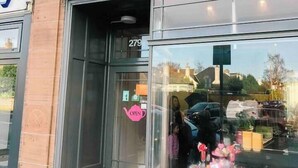 A storefront with the sign "BON Tea.com" and a pink sign above the door.