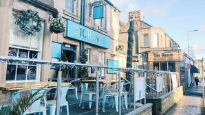 A street view with outdoor seating at a restaurant named 'The Torfin'.