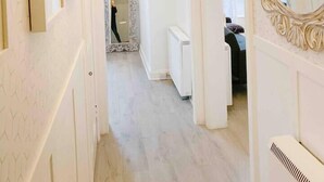 A hallway with a mirror, a radiator, and a door leading to a room.