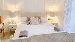 A neatly arranged bedroom with a large bed, two bedside tables, and a chair.