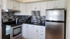 A modern kitchen with white cabinets, stainless steel appliances, a black and white backsplash, and a built-in oven. - Charming 3-bedroom townhome 2 blocks from ocean and bay, in town of Stone Harbor (Stone Harbor)