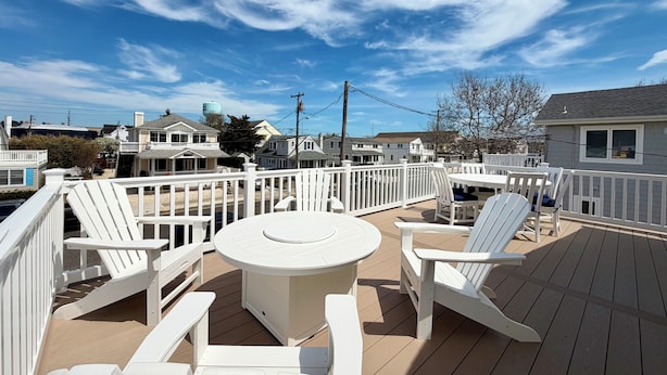 A deck with a round table and white Adirondack chairs, surrounded by a white railing. - Charming 3-bedroom townhome 2 blocks from ocean and bay, in town of Stone Harbor (Stone Harbor)